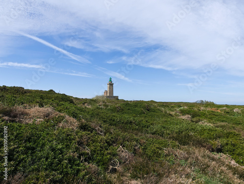 Obraz na płótnie green hill with the Cap Fréhel lighthouse in Brittany in the background