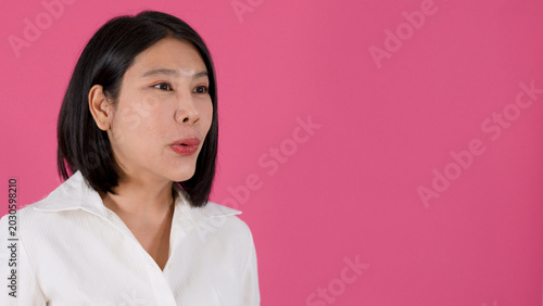 Foto Expressive Asian Woman Talking Against a Vibrant Pink Studio Background