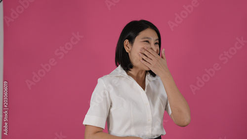 Quadro su tela Cheerful Asian Woman Laughing with Hand Over Mouth Against Pink Background