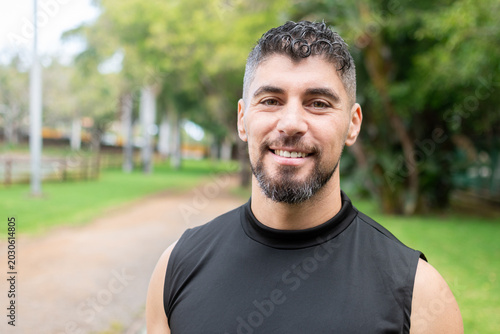 Smiling athletic man standing in park after outdoor workout session