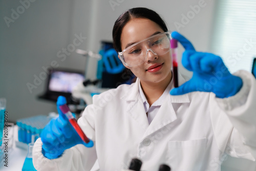 Obraz na płótnie Young laboratory assistant analyzing blood samples for medical diagnosis and hea