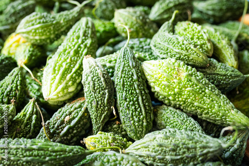 Fotografia A pile of fresh green bitter melons showcasing detailed bumpy texture at a local market stall