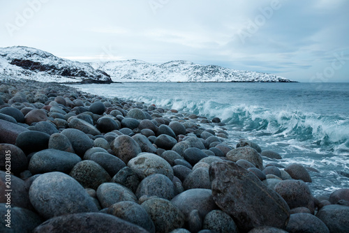 Foto Rocky beach with round stones in winter Teriberka Arctic ocean coast background