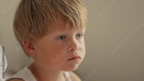 Cute blond boy eating breakfast and watching tv