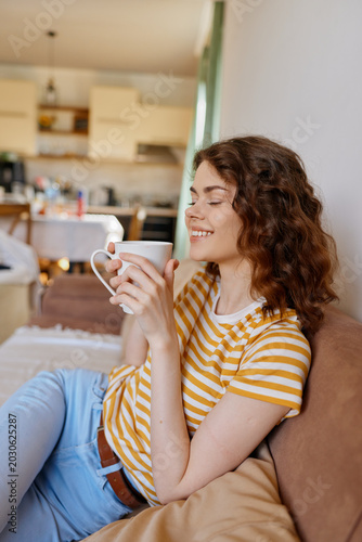 Photos A woman relaxing at home, sipping coffee from a mug in a bright living space