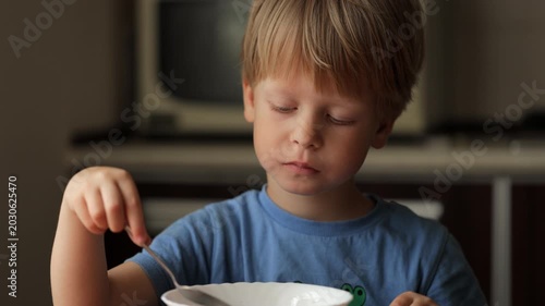 Sleepy little boy eating breakfast cereal