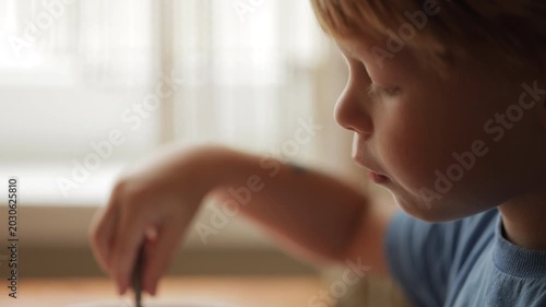 Close-up of little boy eating breakfast with spoon