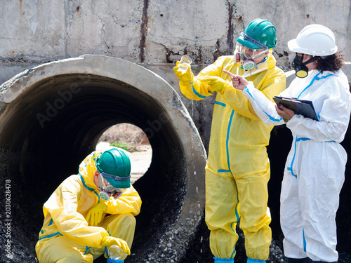 Fotografía Environmental engineers in chemical protective suits are collecting samples of contaminated water, ecologically and industrially, from nearby areas for testing