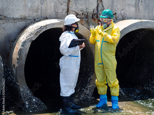 Canvastavla Environmental engineers in chemical protective suits are collecting samples of contaminated water, ecologically and industrially, from nearby areas for testing