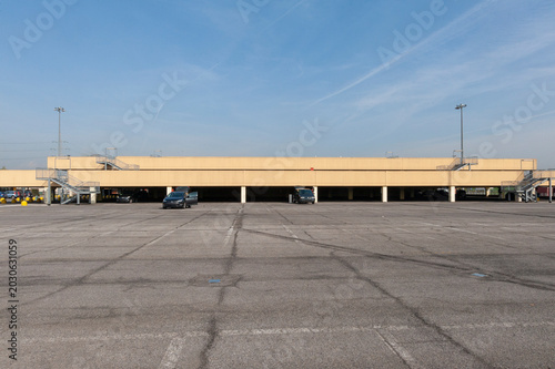 Bild auf Leinwand Ampio parcheggio vuoto con superficie in cemento, linee di demarcazione e pochissimi veicoli presenti