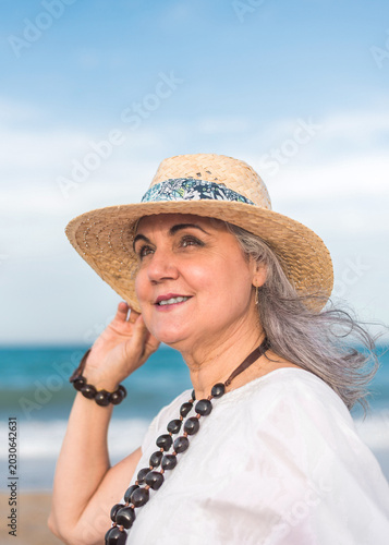 Smiling senior woman wearing a hat enjoying summer vacation at beach