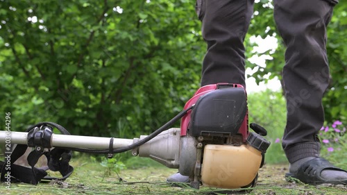 A farmer's hands start a gas-powered mower before work. Haymaking time in the countryside.