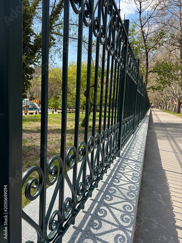 A sturdy black metal fence runs along the sidewalk.