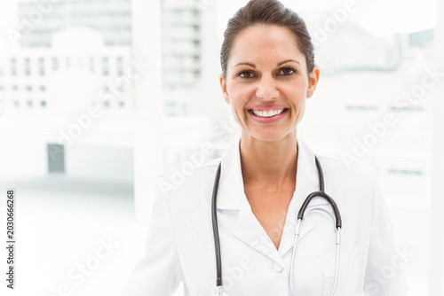 Fotografija Mid adult female doctor standing smiling in clinic wearing labcoat stethoscope V