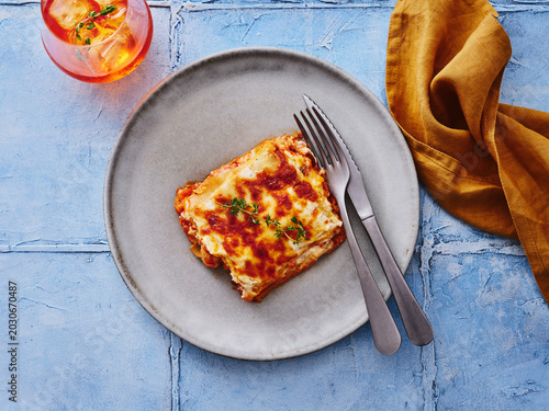 The image showcases a serving of lasagna topped with cheese and fresh herbs on a plate. This versatile dish is ideal for restaurant menus, promotional materials, or food delivery services