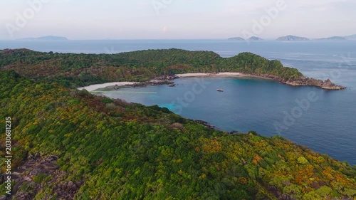 Aerial view of a tropical paradise beach island with green forest eco system and crystal clear turquoise water and white sand beach background	