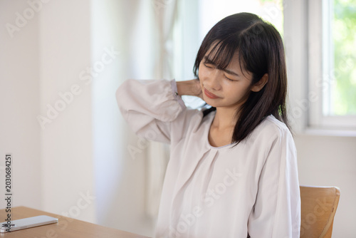 Cuadro en lienzo Asian woman frowning while touching her shoulder in bright room