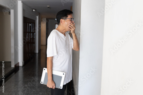 Photos A tired sluggish sleepy and yawning South East Asian man tries to finish his wor