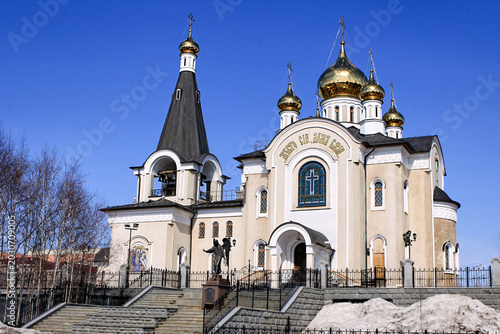 Foto Orthodox church with golden domes and bell tower under a vivid blue sky in a snowy urban setting
