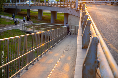 Bild auf Leinwand Cyclist riding down a ramp under a modern bridge