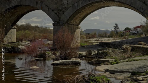 Ancient stone bridge arches crossing a low river