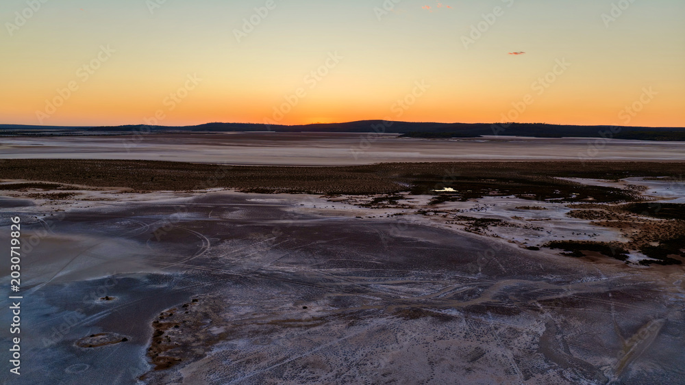 Fototapeta premium Lake Cowan at Sunset, Norseman, Western Australia – 4K Aerial Drone View of Inland Salt Lake, Calm Water, Vast Horizon, Forest, Remote Landscape and Soft Evening Sky in Australia Inland