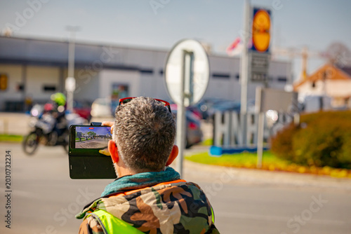 Man photographer taking photo a group of cyclists as they ride on city street