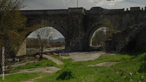 Old stone bridge with multiple arches spanning a dry riverbed