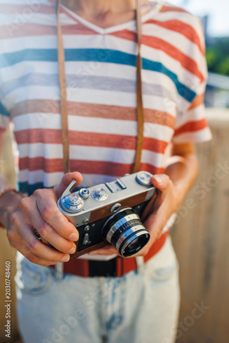 young girl with a camera.  the photographer adjusts the camera. Stylish girl with a film camera. film camera close up.