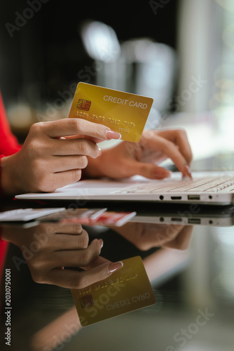 Woman holding credit cards while making a successful online payment on laptop computer, representing e-commerce, digital banking, and secure online shopping at home.
