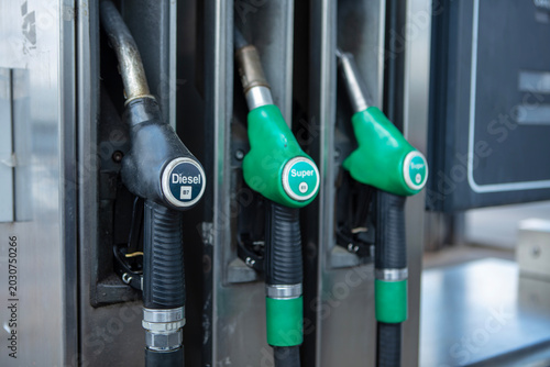 Pump nozzles at a gas station, close-up, daylight.
