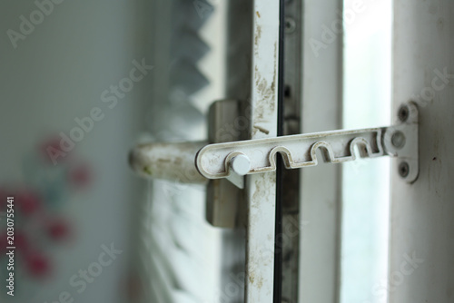 Foto Close up of a domestic white window handle with a safety restrictor lock against a blurred background with daylight