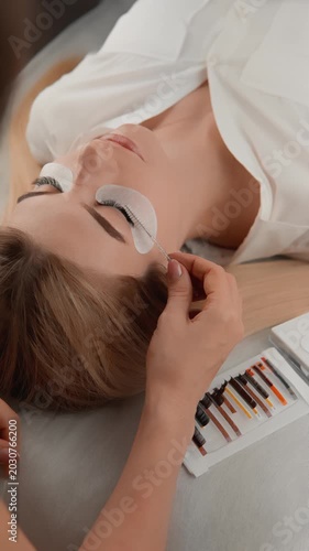 Closeup of a beauty procedure where a client enjoys eyelash extensions, highlighting the precision and care of the technician. The serene atmosphere emphasizes relaxation and self care trends