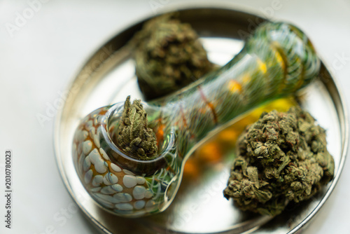Φωτογραφία Top down view of a packed glass smoking pipe and dry cannabis buds inside a metal stash tray