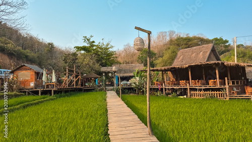 Foto Rustic Wooden Walkway with Lanterns Leading to Thatched Huts in Luang Prabang La