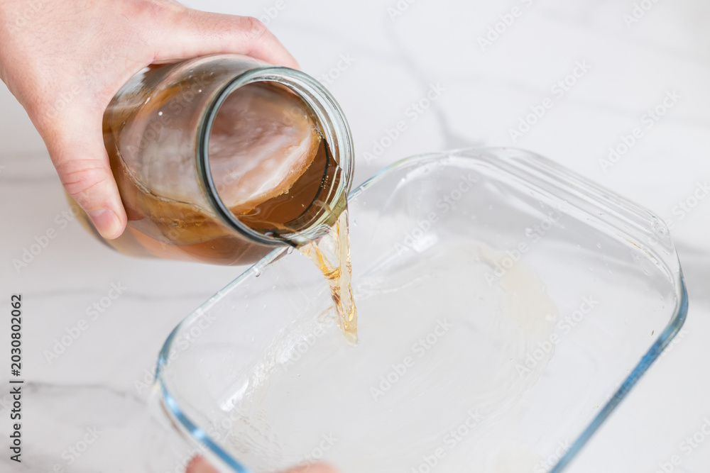 Photography Pouring kombucha liquid with visible scoby from jar for fermentation tutorial ba