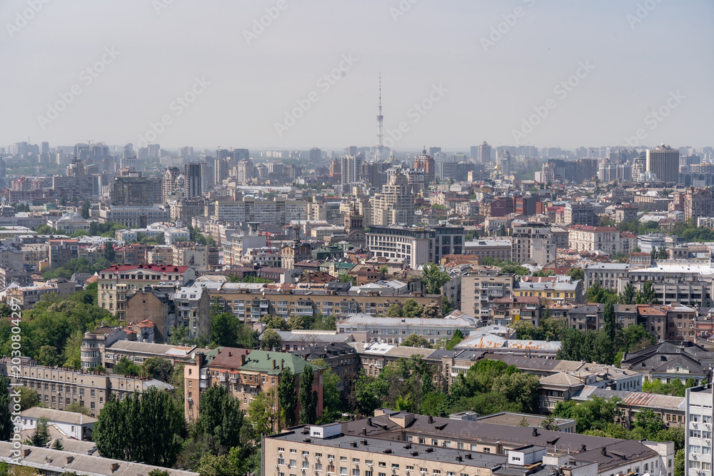 Fototapeta premium Aerial cityscape of Kyiv Ukraine with TV tower and dense urban architecture, panoramic view of city skyline
