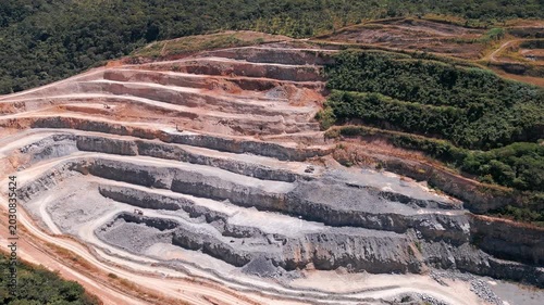 Terraced quarry near Brasília, Distrito Federal, Brazil, revealing exposed stratified rock, erosion scars, deforestation, extraction benches, and severe Cerrado landscape transformation from mining