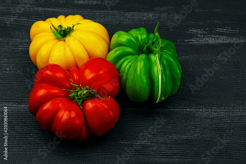 Billede på lærred Multicolored homegrown heirloom beefsteak tomatoes on a dark wooden background