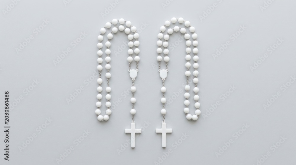 Fototapeta premium Two White Rosaries Arranged Side by Side on a Light Purple Background.