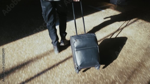 Unrecognizable person walking with his carry-on suitcase through an underground parking lot
