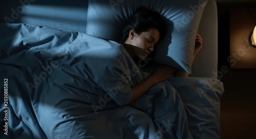 Peaceful Young Woman Sleeping Soundly in Bed at Night with Soft Moonlight and Warm Lamp Light in a Dark Bedroom