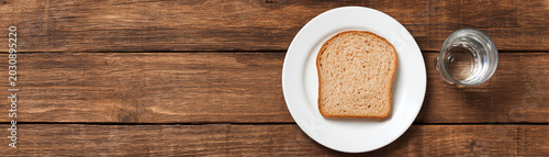 Food security crisis bread slice plate wooden table concept with copy space simple meal and water glass symbolizing hardship and support