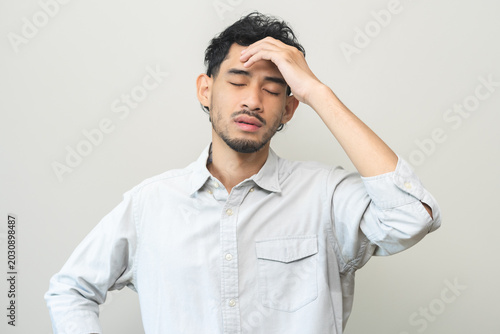 Dizzy asian young man, male headache or migraine pain suffering from vertigo or sick, holding head with hand, health problem of brain or inner ear not balance, standing isolated on white background.