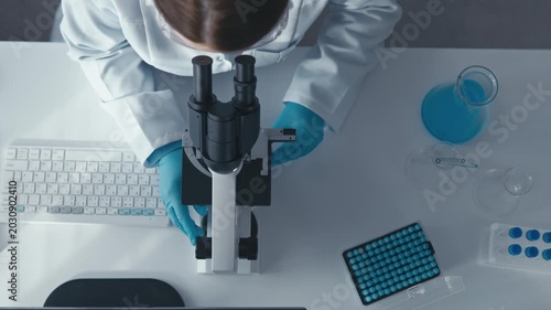 Top view of a laboratory workspace featuring a scientist using a keyboard and microscope, emphasizing precision and professionalism. The scene reflects cutting edge research and laboratory workflow