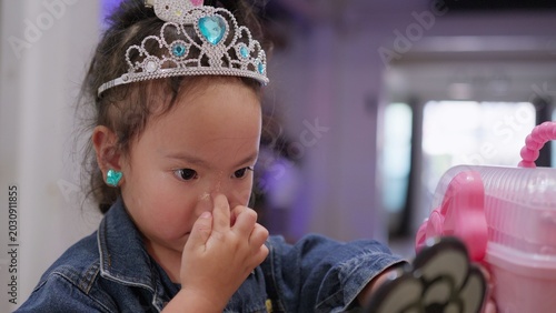 Foto A curious toddler girl plays dress-up with a tiara and glitter makeup, exploring her imagination and developing self-expression while playing indoors