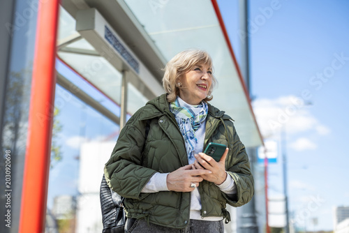 Woman using her smartphone while waiting for a bus in the city
