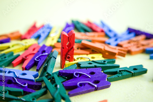 Tableau sur toile Colorful Wooden Clothespins on Yellow Background with One Red Pin Standing Uprig
