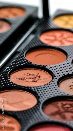 Close-up view of a makeup palette with various shades of eyeshadow in a black case