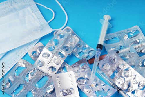 Used empty blister packs and medical waste on blue background. Concept of healthcare waste management, environmental pollution, safe recycling of plastic medicine packaging and eco pharmacology.  